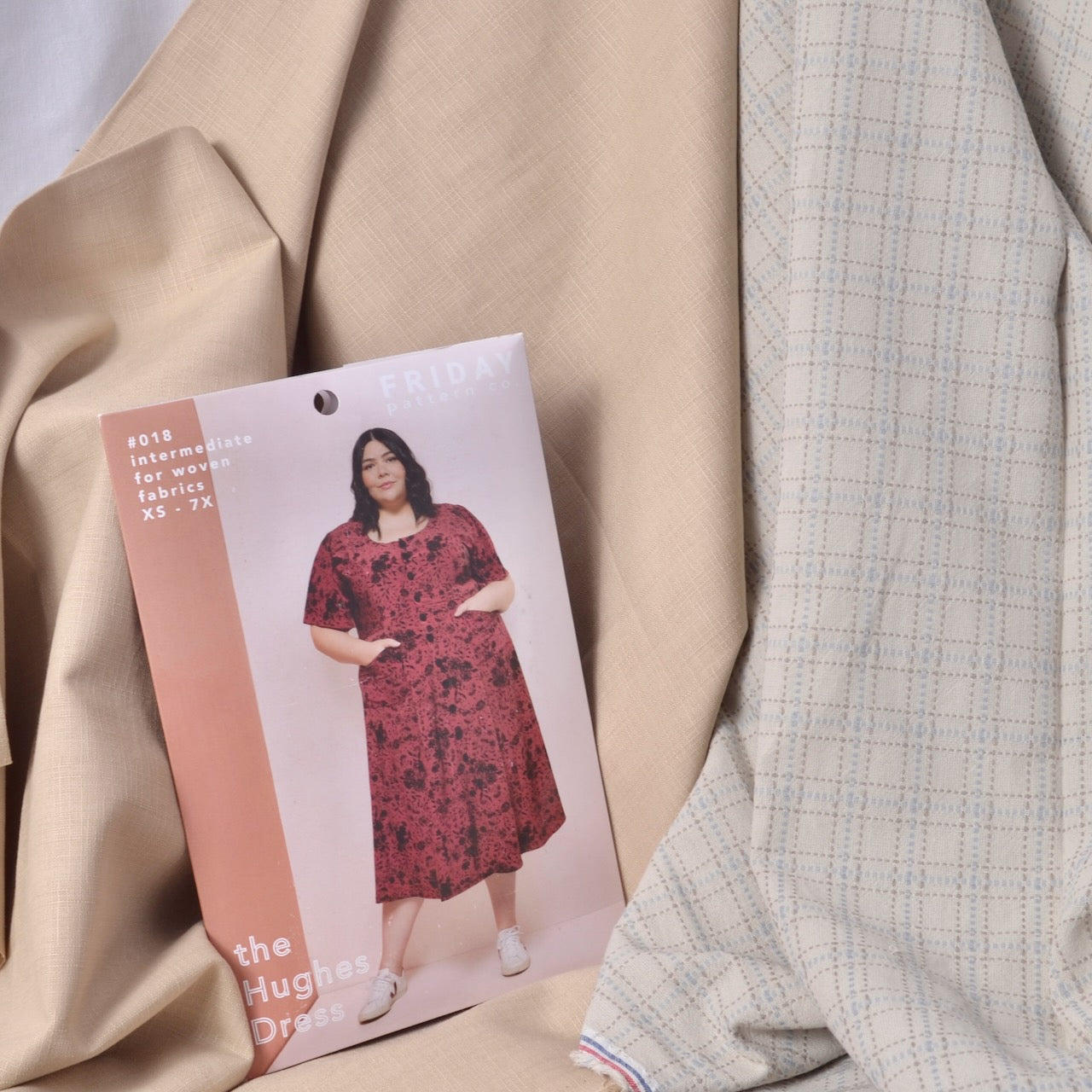 'The Hughes Dress' by Friday is displayed on top of dobby cotton and yarn dyed cotton fabrics