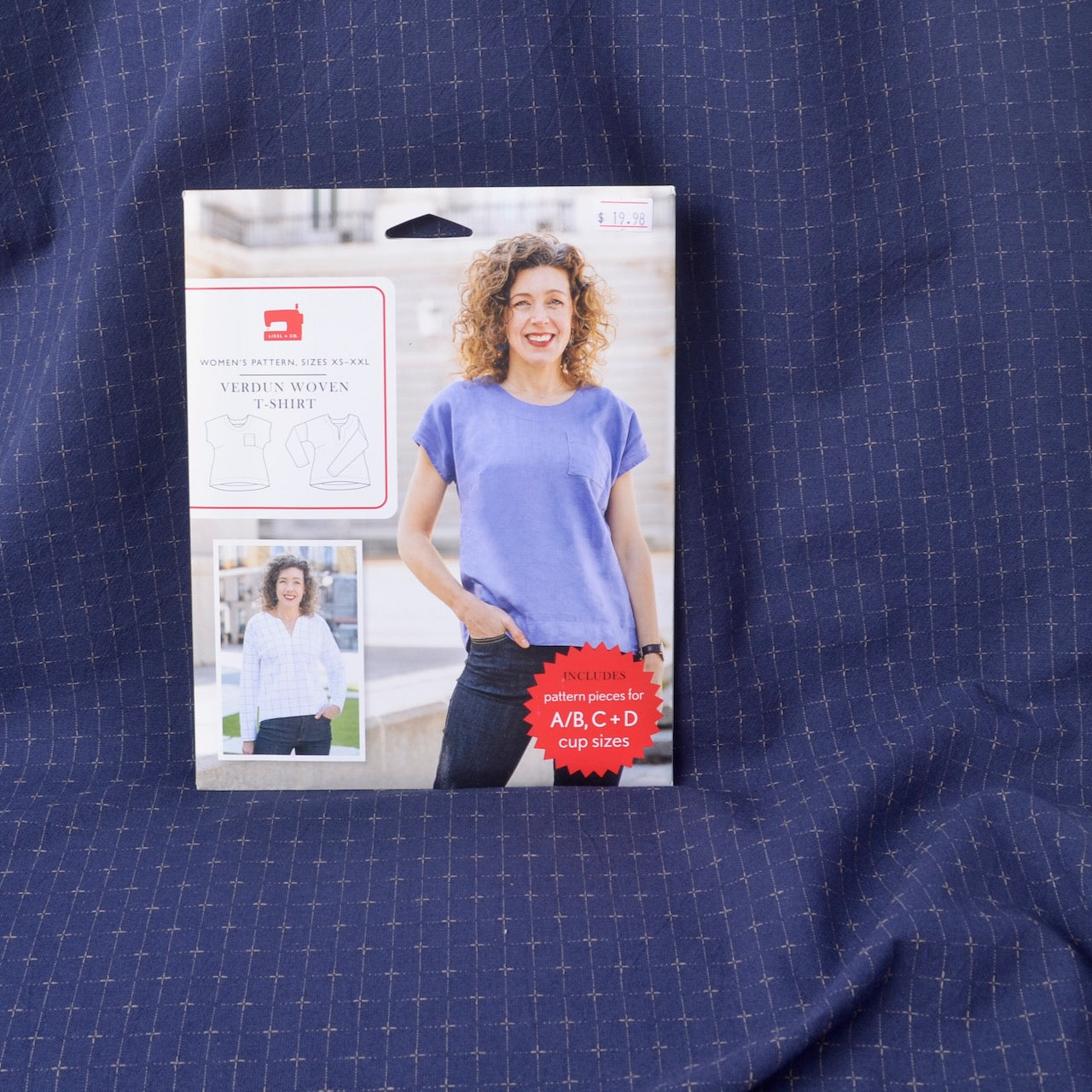 a sewing pattern for a women's short-sleeve crewneck shirt, displayed on a textured navy blue dyed yarn cotton fabric 