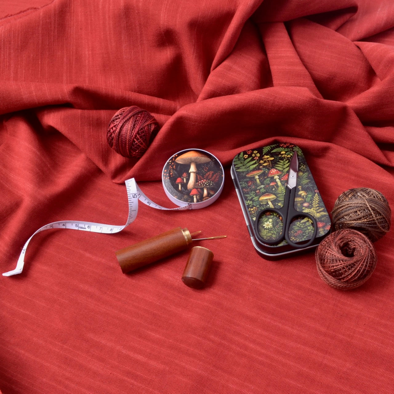 forest mushroom print on tape measure shown with other sewing notions and threads