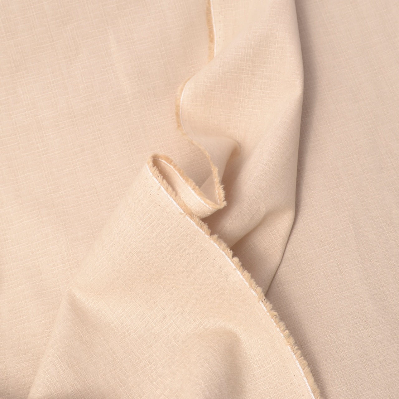 A close-up of draped light beige  dobby fabric with a visible woven texture and raw frayed edges.