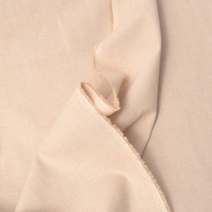 A close-up of draped light beige  dobby fabric with a visible woven texture and raw frayed edges.