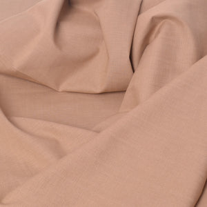 A close-up of draped dobby fabric in a soft warm beige or blush-tan color, showing the woven texture and folds.