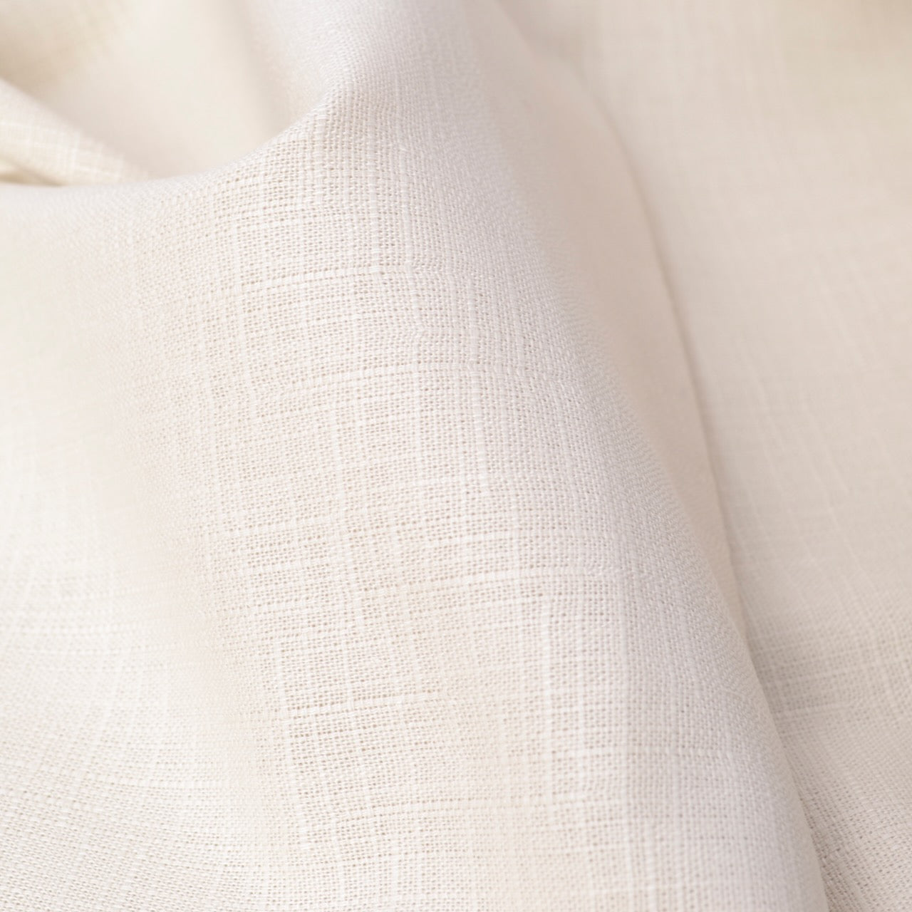 A close-up of draped off-white fabric with a subtle woven texture, showing soft folds and light shading.