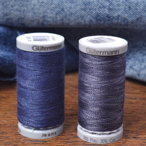 Two spools of Glütermann sewing thread in  denim blue shades