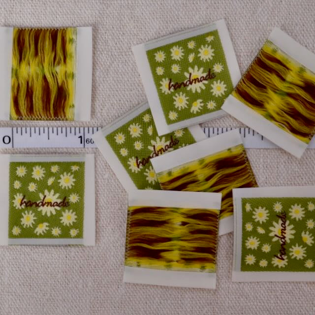 one inch cloth labels with text reading "handmade" bright green with daisies