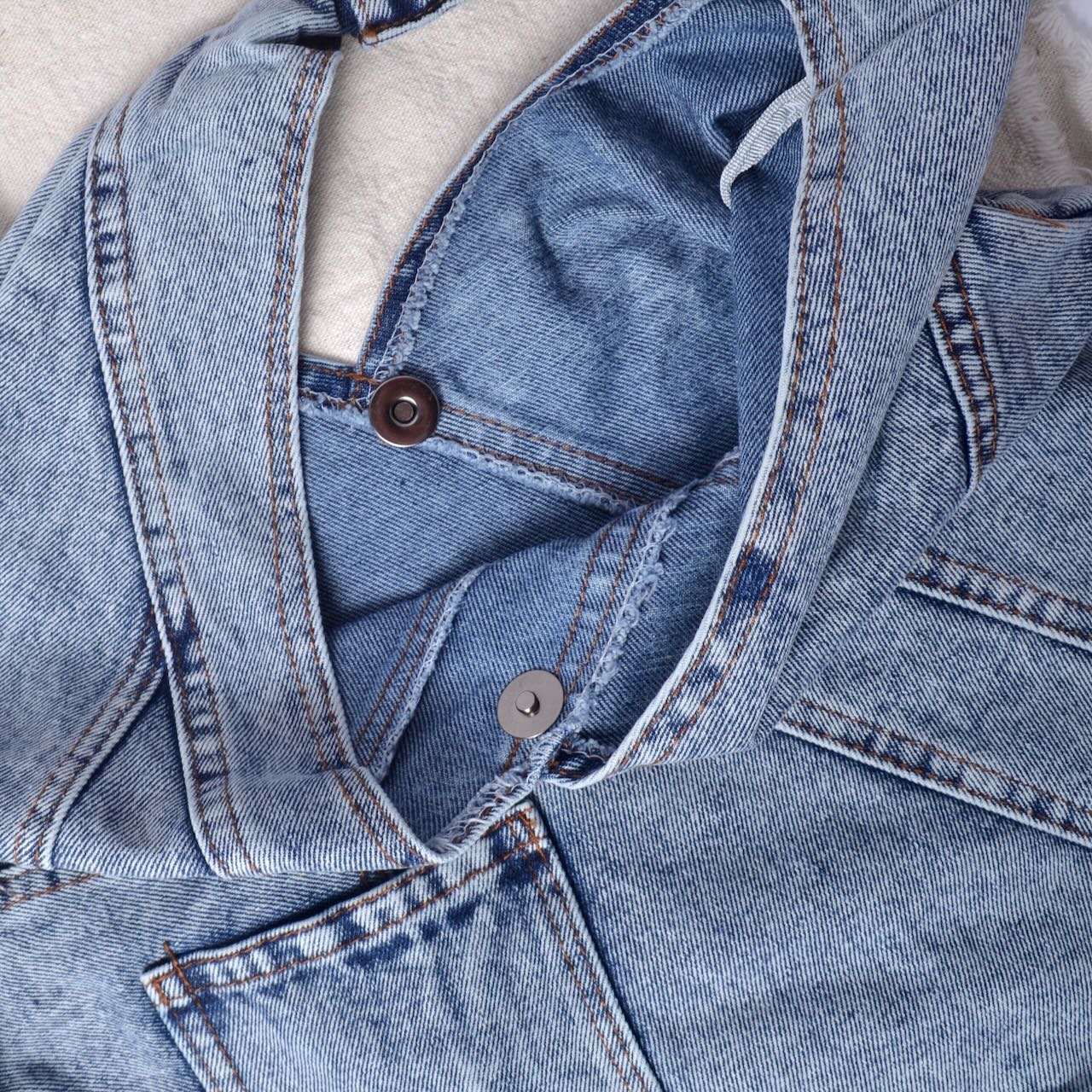 close up showing ietails of denim bag finishing and snap closure