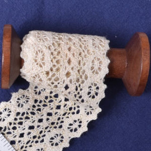 Wooden spool with lace fabric on a blue background