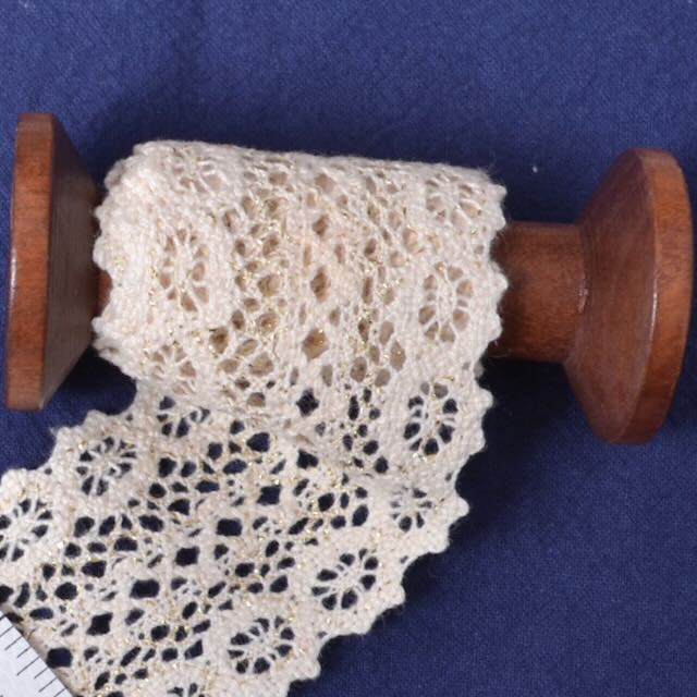 Wooden spool with lace fabric on a blue background