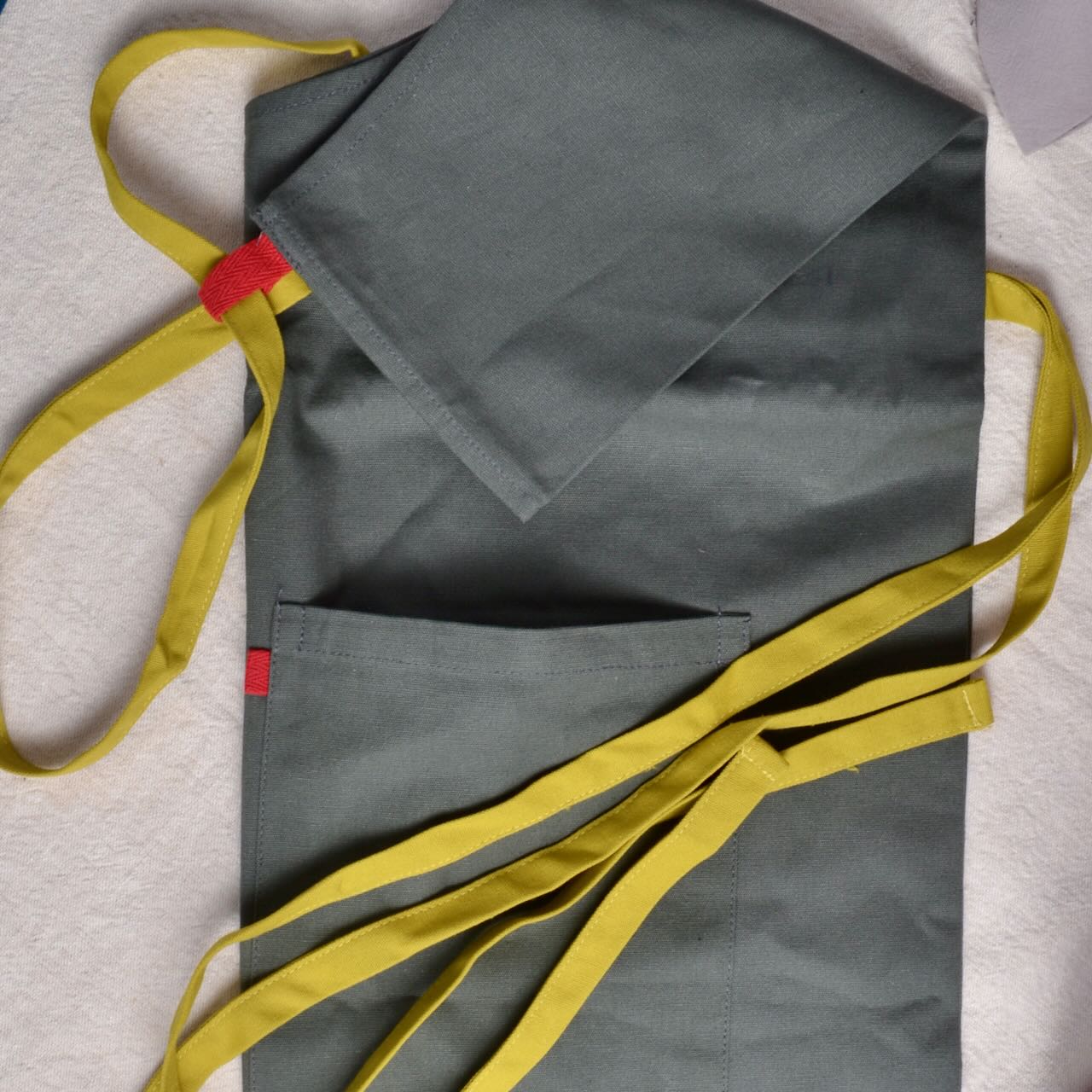 dark olive Cotton Apron Stitching with mustard straps and red tags for studio or kitchen use