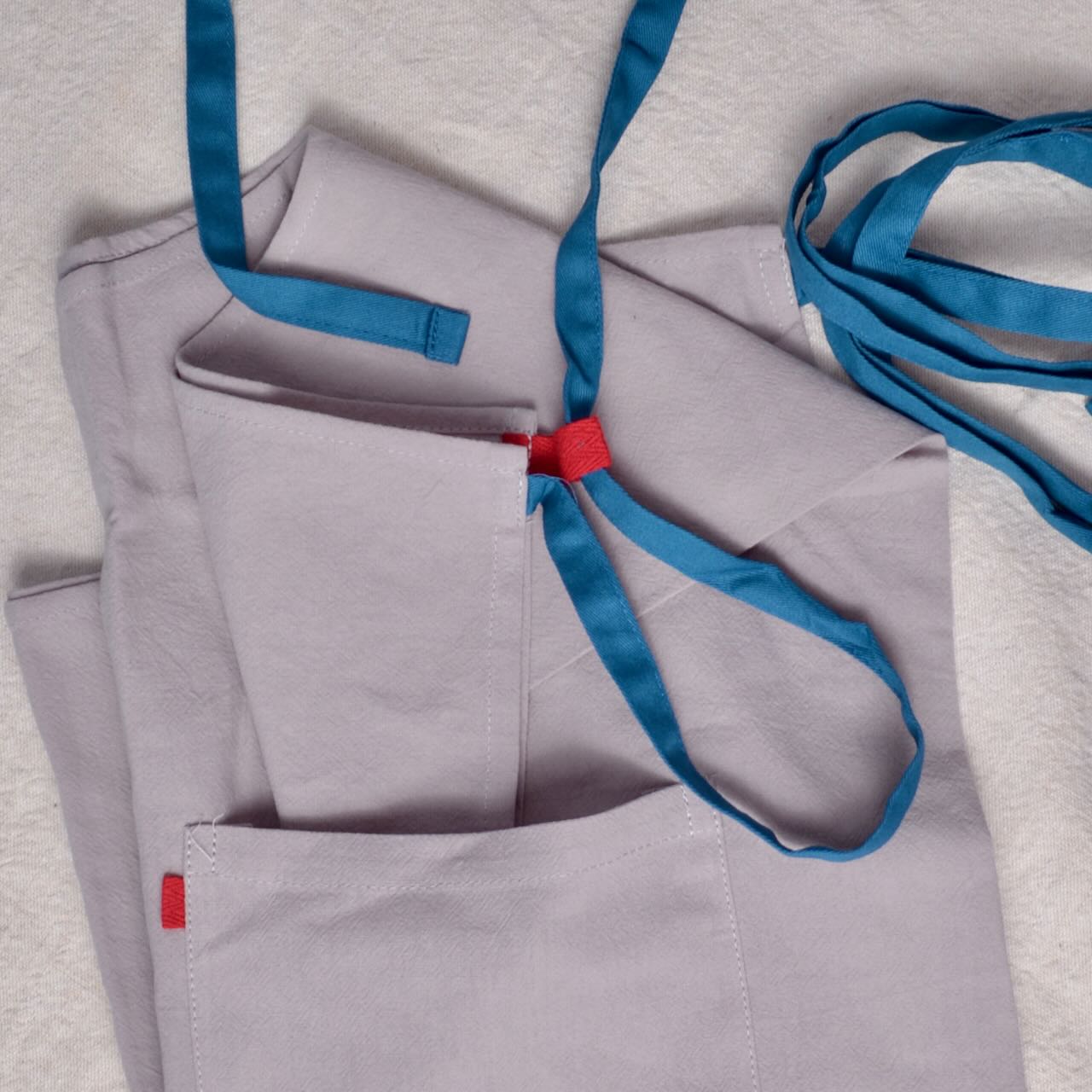 Gray apron with blue straps and red labels 
