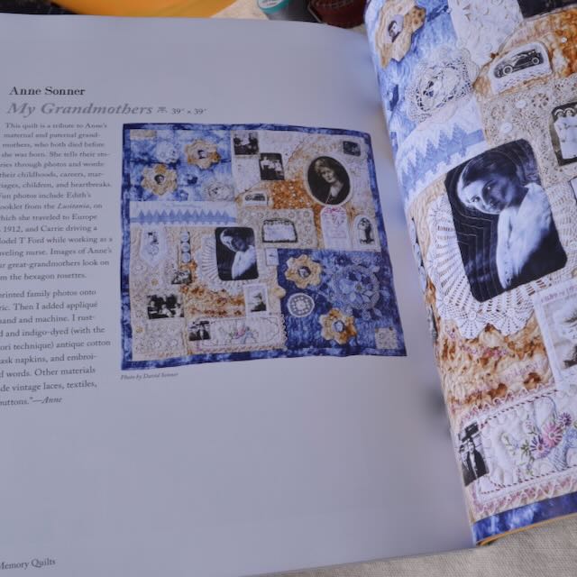 Book open to a page with a quilt pattern and fabric swatches on a table.