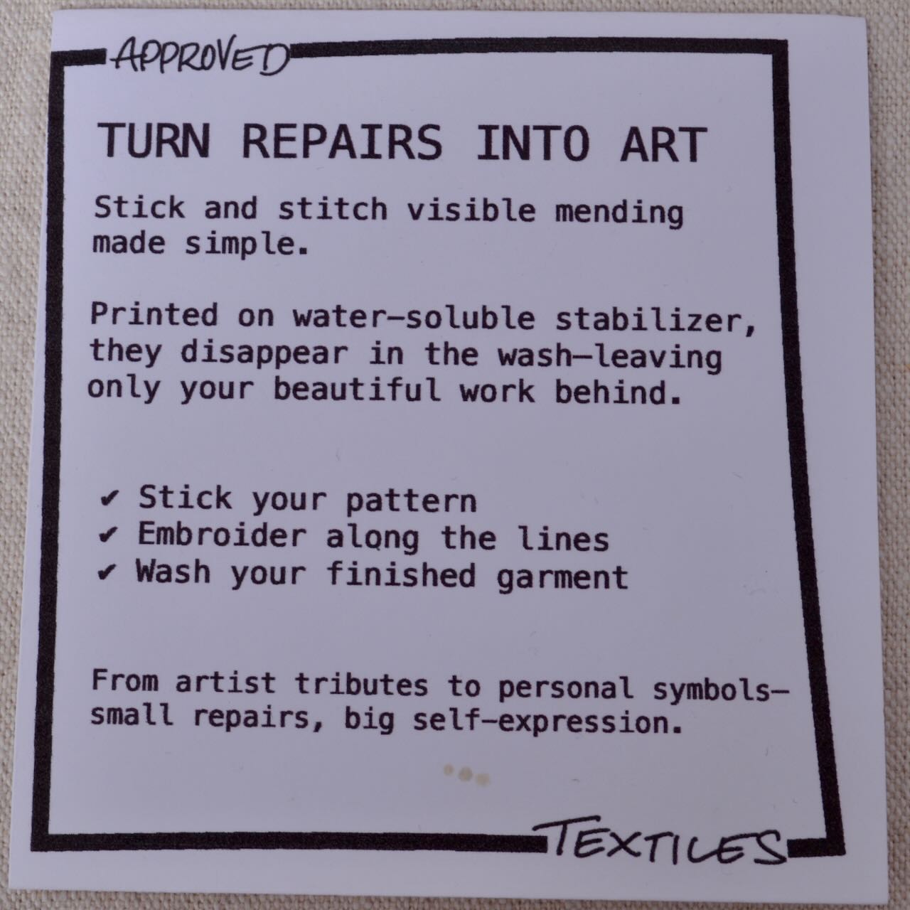 Textile label with instructions on turning repairs into art using water-soluble stabilizer.