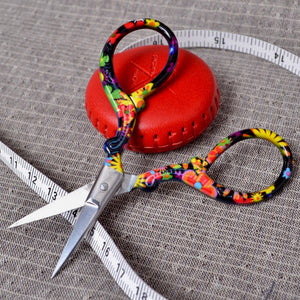 Red measuring tape and colourful embroidery scissor