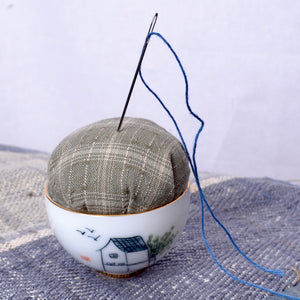 Pincushion with a needle and thread in a ceramic pin bowl cushion