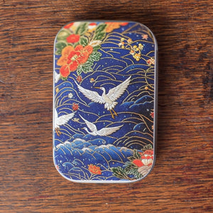 Decorative tin with crane and floral design on the surface