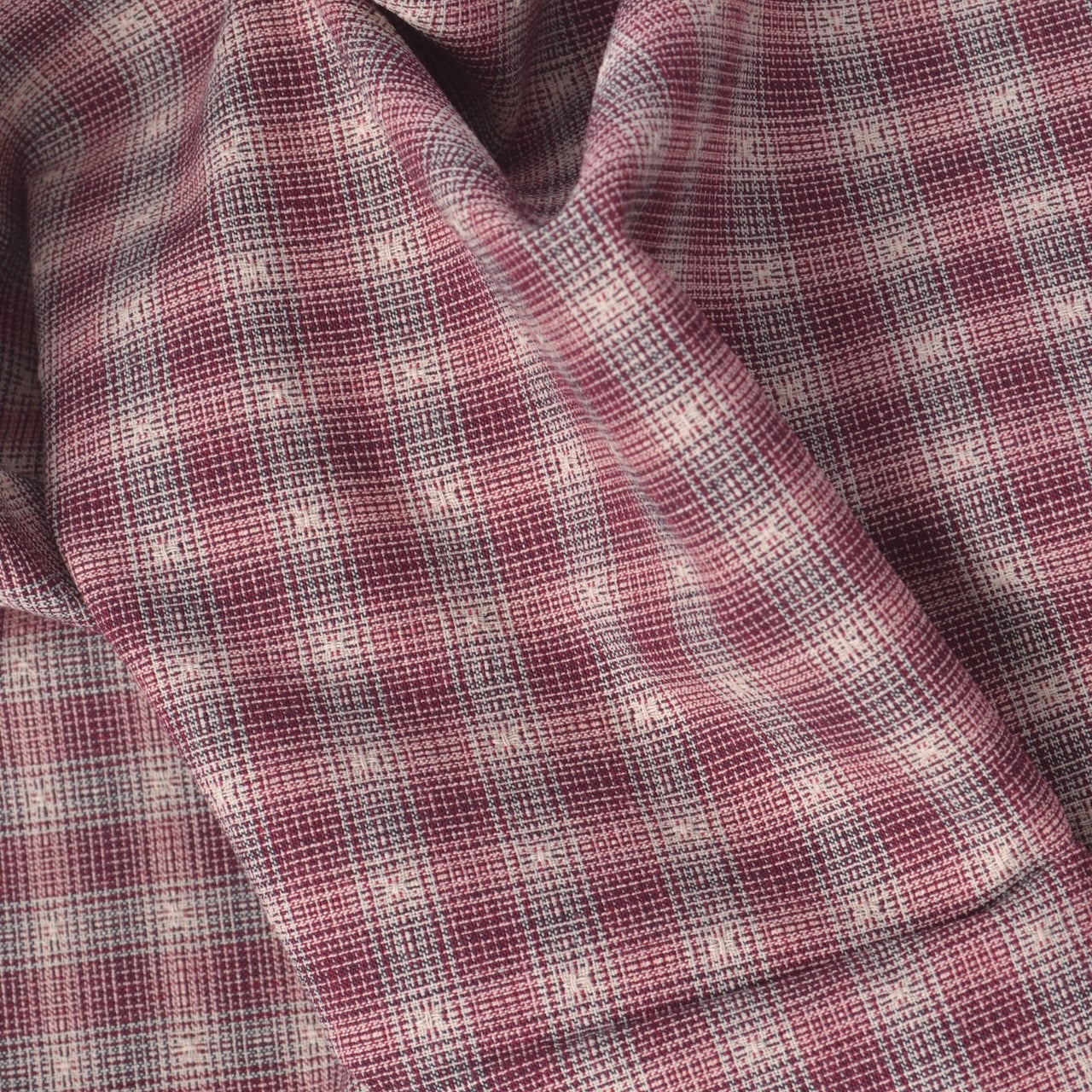 A close-up of draped yarn dyed cotton fabric with a dusty rose and white plaid pattern.