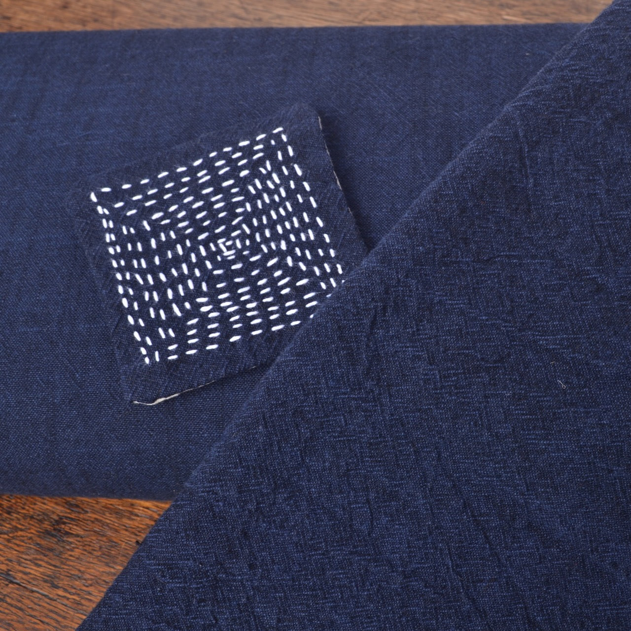showing the fabric new on the bolt, machine washed and dried in foreground, and sashiko stitched