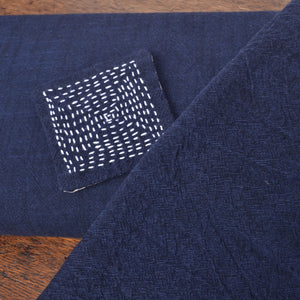 showing the fabric new on the bolt, machine washed and dried in foreground, and sashiko stitched